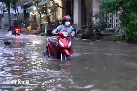 Người dân phải dắt xe bị chết máy qua dòng nước ngập trên đường Phú Thuận (Quận 7). (Ảnh: TTXVN phát)