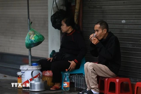 Thưởng thức cốc trà nóng trong mưa lạnh trên phố Trần Nhân Tông. (Ảnh: Hoàng Hiếu/TTXVN)