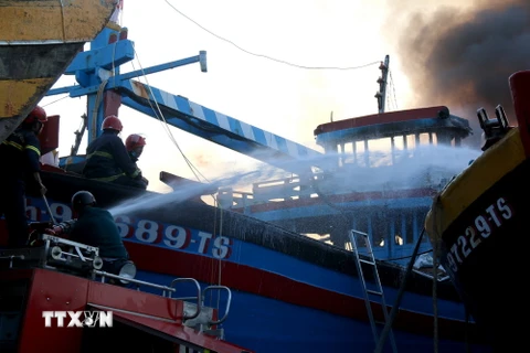 Tuy đám cháy được khống chế, nhưng Lực lượng chức năng vẫn túc trực và bơm nước lên tục vào bên trong các tàu nhằm phòng ngừa lửa bùng phát trở lại. (Ảnh: Nguyễn Thanh - TTXVN)