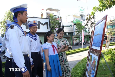 Các chiến sỹ và học sinh xem ảnh tại triển lãm ảnh “Hoàng Sa - Trường Sa trong lòng Quảng Ngãi”. (Ảnh: Đinh Hương/TTXVN)