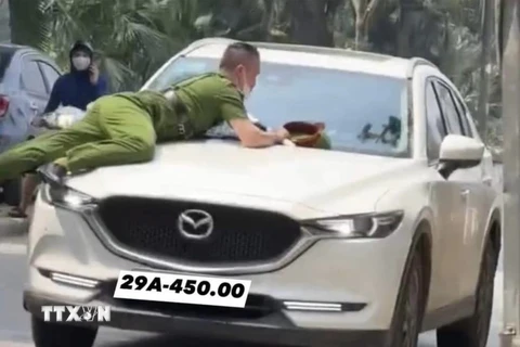 Hình ảnh vụ việc hất văng chiến sỹ Công an lên nắp capo xe ôtô. (Ảnh: TTXVN phát)