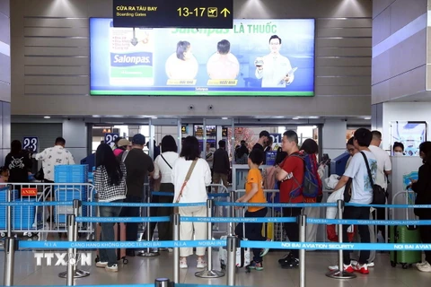 Hành khách xếp hàng đợi vào khu vực kiểm tra an ninh tại sảnh E, sân bay quốc tế Nội Bài. (Ảnh minh họa: Huy Hùng/TTXVN)