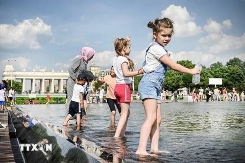 Các em nhỏ tránh nóng bên đài phun nước tại Moskva, Nga. (Ảnh: Getty Images/ TTXVN)