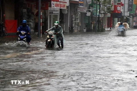 Nước ngập tại nhiều tuyến đường trong thành phố Huế khiến việc đi lại của người dân khó khăn. (Ảnh: Đỗ Trưởng/TTXVN)