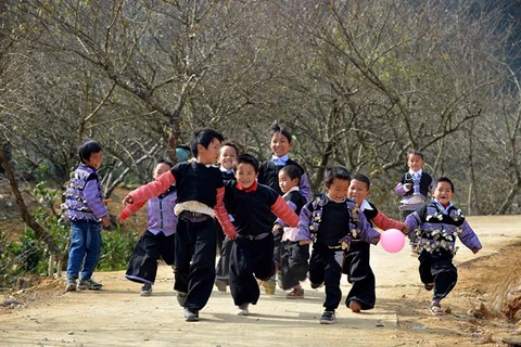 Trẻ em tung tăng đi chơi Tết trong trang phục truyền thống sặc sỡ. (Ảnh: Thanh Hà/TTXVN)