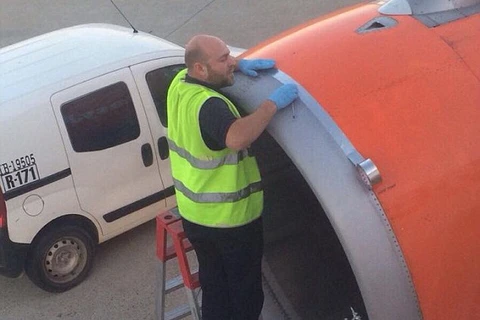 Nhân viên sân bay dùng băng dính để dán lên mép nối trên vỏ tuabin trước khi máy bay cất cánh. (Nguồn: Daily Mail)
