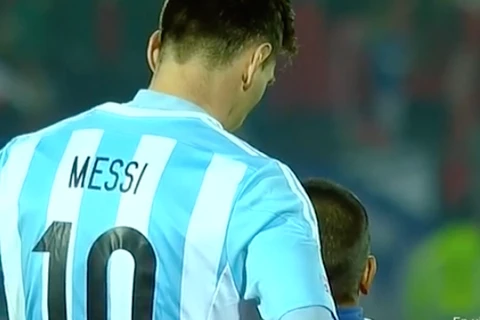 Messi không bộc lộ bất cứ cảm xúc nào khi chụp ảnh cùng cổ động viên nhí Chile. (Nguồn: scoopnest.com)