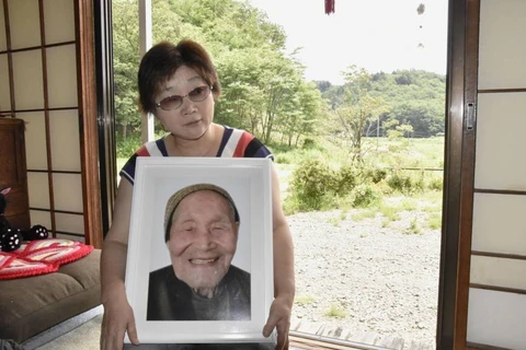 Người thân ôm di ảnh của cụ Fumio Okubo. (Nguồn: Kyodo)