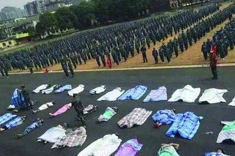 Các sinh viên Trung Quốc với hình phạt quấn chăn và nằm trên nền đất dưới cái nắng gay gắt. (Nguồn: CCTV News)
