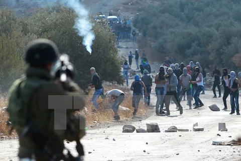 Binh sỹ Israel bắn đạn hơi cay vào người biểu tình Palestine ở khu Bờ Tây. (Ảnh: AFP/TTXVN)