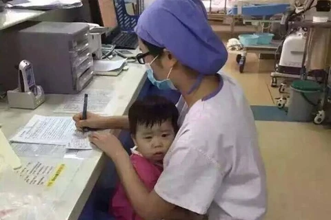 Hình ảnh nữ y tá ôm bé gái mồ côi khi làm việc. (Nguồn: CCTV News)