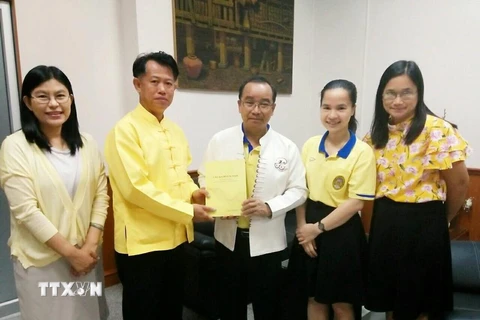 Tiến sỹ Boonlue Chaimano, Chủ nhiệm bộ môn tiếng Thái thuộc Đại học Lampang Rajabhat tặng sách cho Hiệu trưởng Đại học Lampang Rajabhat Somkiat Saithanoo. (Ảnh: Ngọc Quang/TTXVN)