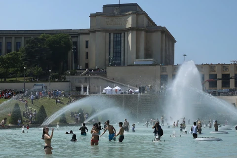Người dân giải nhiệt tại một đài phun nước ở Paris ngày 26/6. (Ảnh: THX/TTXVN)