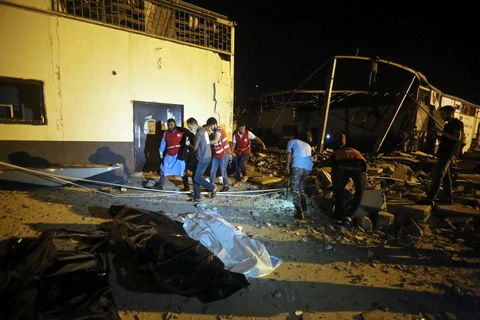 Chuyển thi thể nạn nhân tại hiện trường vụ không kích nhằm vào khu tạm giữ người di cư ở Tajoura, ngoại ô thủ đô Tripoli, Libya ngày 3/7. (Ảnh: AFP/ TTXVN)