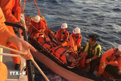 Xuồng cứu nạn của tàu SAR 274 chuyển tiếp nạn nhân từ tàu cá lên tàu SAR để về bờ. (Ảnh: TTXVN phát)