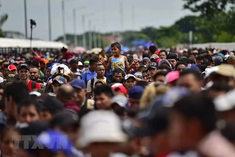 Người di cư trong hành trình tới Mỹ tại cây cầu biên giới Guatemala-Mexico. (Ảnh: AFP/ TTXVN)