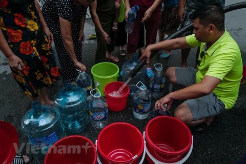 Người dân xếp hàng lấy nước sạch. (Ảnh: PV/Vietnam+)