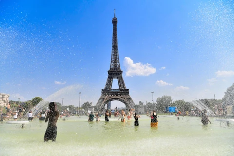 Người dân tránh nóng bên vòi phun nước tại Paris, Pháp. (Ảnh: THX/TTXVN)