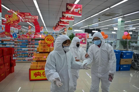 Nhân viên tại một cửa hiệu bán thuốc mặc trang phục phòng dịch viêm phổi do virus corona mới khi phục vụ khách hàng tại thành phố Vũ Hán. (Ảnh: AFP/TTXVN)