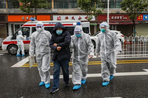 Nhân viên y tế hỗ trợ bệnh nhân nhiễm COVID-19 tới bệnh viện ở Vũ Hán, tỉnh Hồ Bắc, Trung Quốc. (Ảnh: AFP/TTXVN)