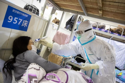 Nhân viên y tế kiểm tra thân nhiệt một bệnh nhân nghi nhiễm COVID-19. (Ảnh: AFP/TTXVN)
