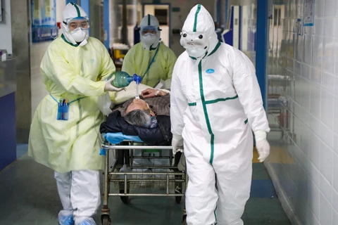 Nhân viên y tế chuyển bệnh nhân nhiễm dịch viêm đường hô hấp cấp COVID-19 tới bệnh viện Vũ Hán, tỉnh Hồ Bắc. (Ảnh: Reuters/TTXVN)