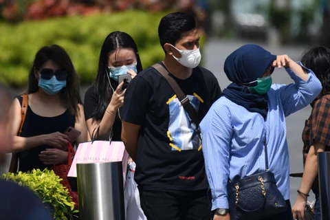 Người dân đeo khẩu trang phòng dịch viêm đường hô hấp cấp do virus COVID-19 tại Singapore. (Ảnh: AFP/TTXVN)