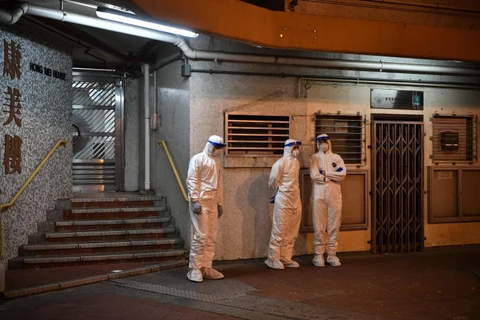 Nhân viên y tế tiến hành cách ly một khu chung cư tại Hong Kong. (Ảnh: AFP/TTXVN)
