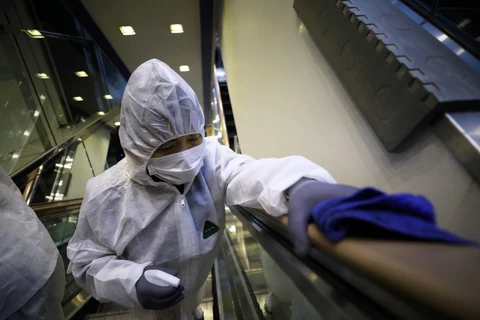 Nhân viên khử trùng tay nắm cầu thang tại một trung tâm thương mại ở Seoul, Hàn Quốc nhằm ngăn chặn sự lây lan của COVID-19. (Ảnh: THX/TTXVN)