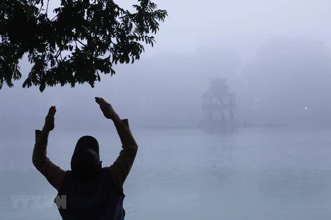 Một người đàn ông tập thể dục bên hồ Hoàn Kiếm, Hà Nội trong sương sớm. (Ảnh: Lâm Khánh/TTXVN)