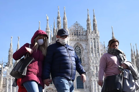 Khách du lịch đeo khẩu trang phòng dịch COVID-19 khi thăm quan Nhà thờ lớn Duomo tại Milan, Italy. (Ảnh: THX/TTXVN)