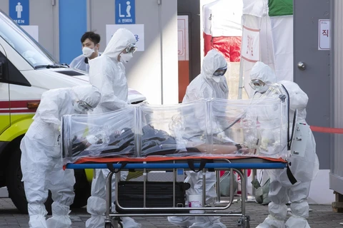 Nhân viên y tế chuyển bệnh nhân nhiễm COVID-19 tới bệnh viện ở Seoul, Hàn Quốc, ngày 11/3. (Ảnh: THX/TTXVN)