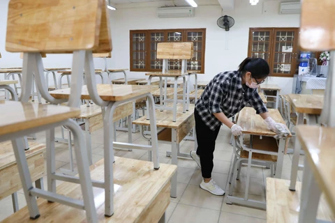 Vệ sinh, khử khuẩn bàn ghế trong lớp học trường THPT Kim Liên, quận Đống Đa, Hà Nội. (Ảnh: Thanh Tùng/TTXVN)