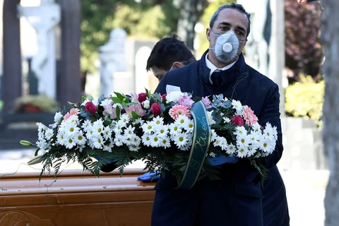 Nhân viên nhà tang lễ vận chuyển quan tài của một nạn nhân nhiễm virus SARS-CoV-2 vào một nghĩa trang ở Bergamo. (Ảnh: Reuters)