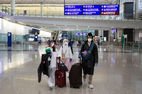 Hành khách đeo khẩu trang phòng lây nhiễm COVID-19 tại sân bay quốc tế ở Hong Kong, Trung Quốc. (Ảnh: AFP/TTXVN)