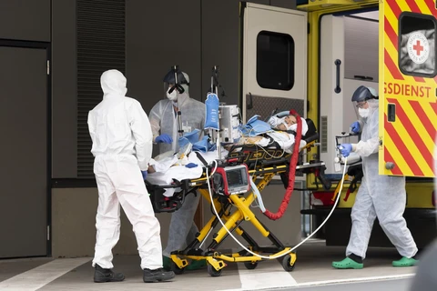 Nhân viên y tế chuyển bệnh nhân mắc COVID-19 từ xe cứu thương vào một bệnh viện ở Dresden, Đức. (Ảnh: AFP/TTXVN)