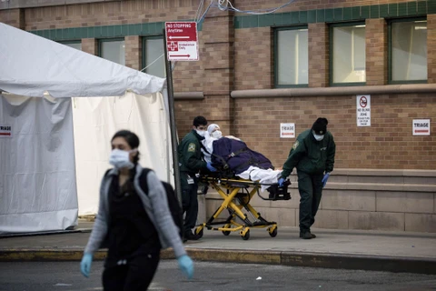 Nhân viên y tế chuyển bệnh nhân nhiễm COVID-19 tới trung tâm y tế ở Brooklyn, New York, Mỹ. (Ảnh: THX/TTXVN)