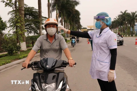 Lực lượng chức năng kiểm tra thân nhiệt cho người tham gia giao thông tại Bắc Ninh. (Ảnh: Thanh Thương/TTXVN)