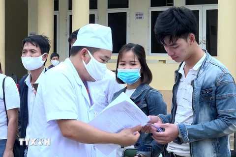 Nhân viên y tế trao giấy chứng nhận hoàn thành thời gian cách ly cho công dân. (Ảnh: Nguyễn Nam/TTXVN)