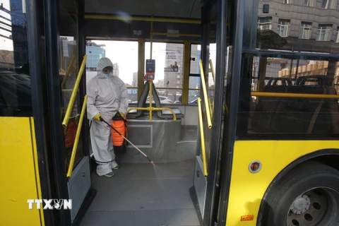 Nhân viên phun thuốc khử trùng trên xe buýt ở Kiev, Ukraine. (Ảnh: THX/TTXVN)