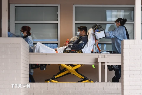 Nhân viên y tế chuyển nạn nhân nhiễm COVID-19 tới bệnh viện ở Brooklyn, New York, Mỹ. (Ảnh: AFP/TTXVN)