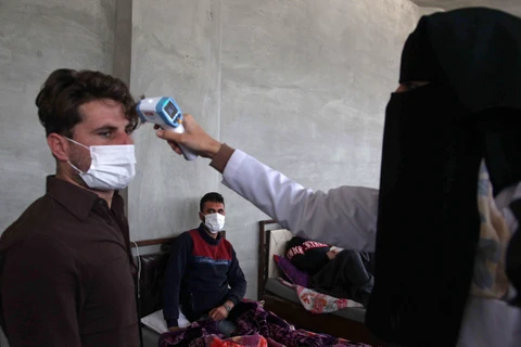 Nhân viên y tế kiểm tra thân nhiệt nhằm ngăn chặn sự lây lan của dịch COVID-19 tại Idlib, Syria. (Ảnh: AFP/TTXVN)