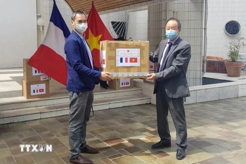 Trao tặng khẩu trang cho ông Vương Hữu Nhân, Chủ tịch Hội người Việt Nam tại Pháp. (Ảnh: Linh Hương/TTXXVN)
