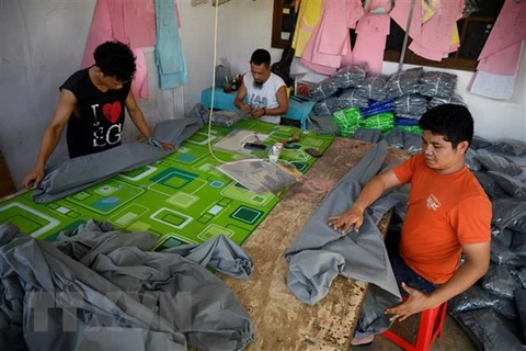 Công nhân may đồ bảo hộ y tế cá nhân và khẩu trang phòng lây nhiễm COVID-19 tại Jakarta, Indonesia. (Ảnh: AFP/TTXVN)