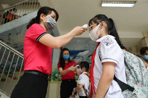 Học sinh trường Tiểu học Nghĩa Tân, quận Cầu Giấy được đo thân nhiệt và sát khuẩn tay trước khi vào lớp. (Ảnh: Thanh Tùng/TTXVN)