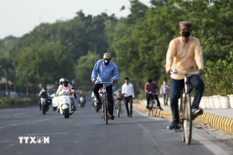 Người dân đeo khẩu trang phòng dịch COVID-19 khi di chuyển trên phố ở New Delhi, Ấn Độ. (Ảnh: AFP/TTXVN)