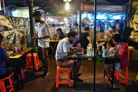 Một quán ăn tại Bangkok, Thái Lan, sử dụng tấm chắn nhựa trên bàn ăn để ngăn chặn sự lây lan của COVID-19. (Ảnh: AFP/TTXVN)