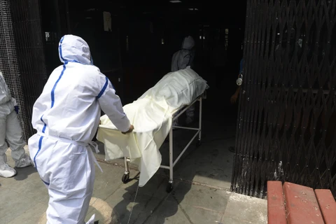 Nhân viên y tế chuyển thi thể bệnh nhân mắc COVID-19 tới khu vực hỏa táng tại New Delhi, Ấn Độ ngày 3/6/2020. (Ảnh: AFP/TTXVN)