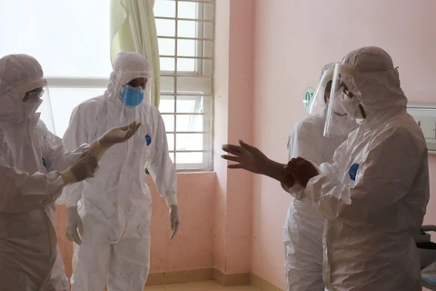  Đội phản ứng nhanh của Bệnh viện Chợ Rẫy hướng dẫn nhân viên y tế Bệnh viện Bà Rịa mặc trang phục bảo hộ. (Ảnh: TTXVN phát)