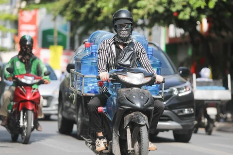Thời tiết nắng nóng, người dân cần trang bị tốt đồ bảo hộ khi ra đường để bảo vệ sức khỏe. (Ảnh: Thanh Tùng/TTXVN)